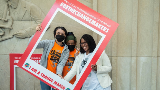 Image of adults and teens taking a picture with a frame that says #BeTheChangeMakers.