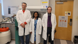 a photo of three people in a lab wearing lab coats