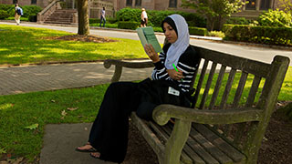 A Seton Hall Student Sitting on a Bench Reading