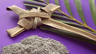A Christian cross, ashes and a palm leaf on a purple background.