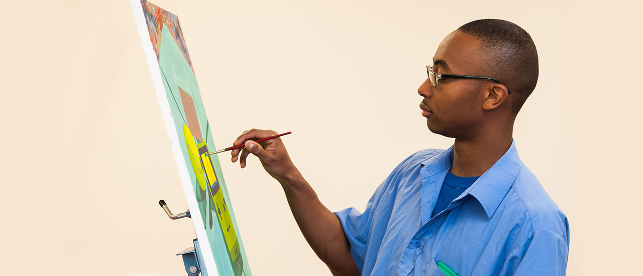 Image of a student painting on a canvas