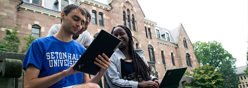DoIt Students on tablet on the University Green. 