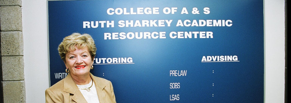 Ruth Sharkey in front of the Ruth Sharkey Academic Resource Center sign. 
