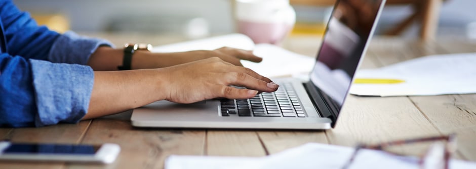 User hands on a laptop keyboard on a desk