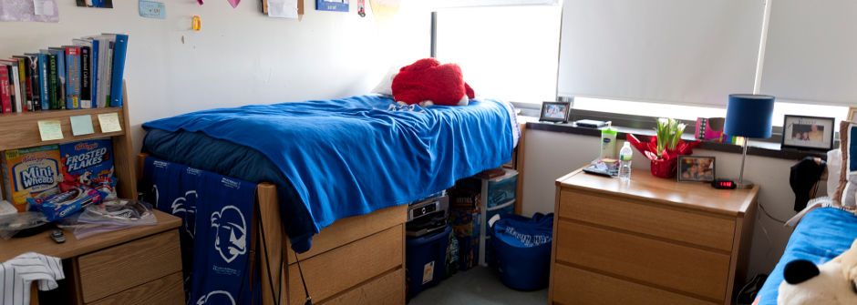 A bed and other miscellaneous items in a dorm room. 