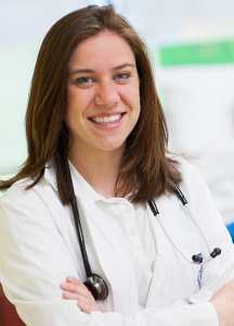 Emily Slate, in her white coat, with a stethoscope.