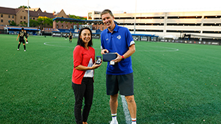 Maria Bouzas being honored pregame with award from men's soccer Head Coach Andreas Lindberg.