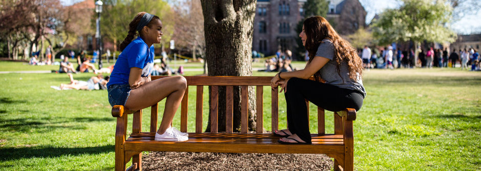 Students talking one-on-one on a bench 