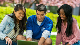 Two students using a laptop outside